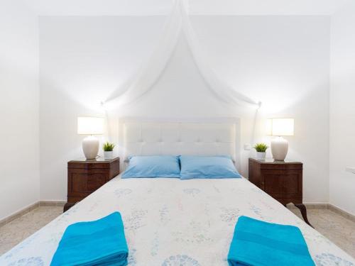 1 dormitorio con 1 cama blanca y 2 sillas azules en Surf Brothers, en Vecindario