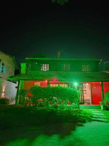 una casa iluminada por la noche con luces rojas y verdes en Casa Mágica, en Praia do Rosa