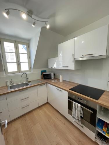 une cuisine avec des armoires blanches et un évier dans l'établissement Appartement tout confort!, à Chartres