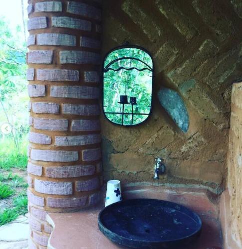 a bathroom with a window and a toilet in a brick wall at Chalé na Chapada, com acesso ao Rio São Miguel in Sao Jorge