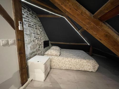- une chambre avec un lit et un mur en briques dans l'établissement BELLEVUE Appartement sous les toits hypercentre climatisé, à Dole