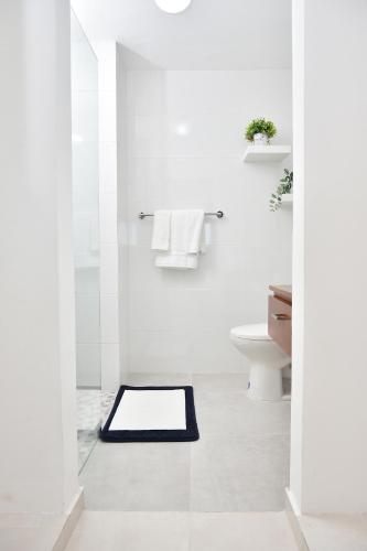 a white bathroom with a black bath mat on the floor at Apartamento en Juan Dolio Tepuy 501 B in Juan Pedro