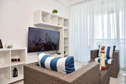 a living room with a television and a couch and chairs at Apartamento en Juan Dolio Tepuy 501 B in Juan Pedro
