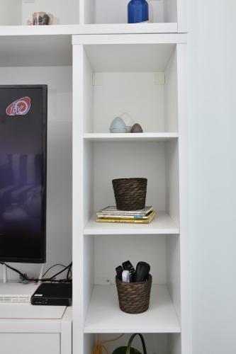 a white book shelf with a tv and baskets at Apartamento en Juan Dolio Tepuy 501 B in Juan Pedro