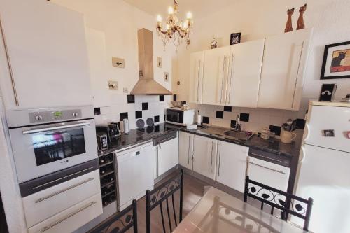 a kitchen with white cabinets and black counter tops at Beautiful apartment between St Rémy and Avignon in Châteaurenard