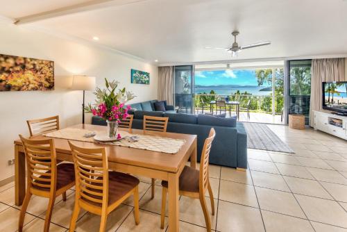 a dining room and living room with a table and chairs at Blue Water Views Apartments in Hamilton Island