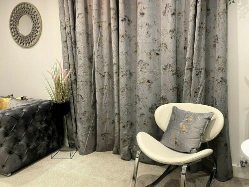 a room with a chair and a curtain at ☆Igloo MagnoliaView Luxe Townhouse + Free Parking☆ in Leeds