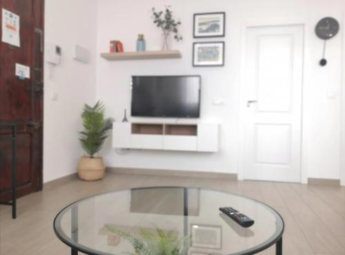 ein Wohnzimmer mit einem TV und einem Glastisch in der Unterkunft Lovely Modern Flat Valencia center in Valencia
