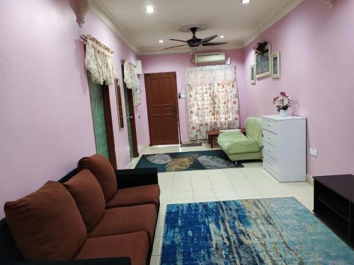 ein Wohnzimmer mit einem braunen Sofa und einem grünen Stuhl in der Unterkunft Homestay D'Lily in Ipoh
