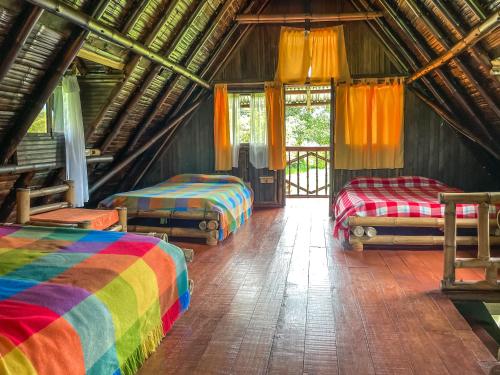 a room with three beds with colorful blankets at Cabaña Numbana San Agustín in San Agustín