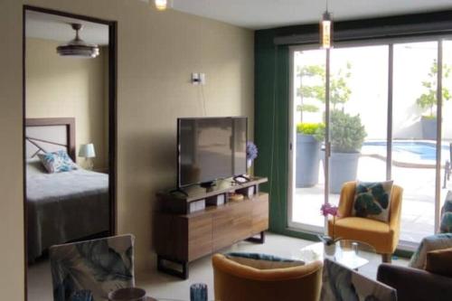 a living room with a television and a bed and a chair at Tu joya Tapatia - AC, alberca y Gym departamento en el corazón de Guadalajara in Guadalajara