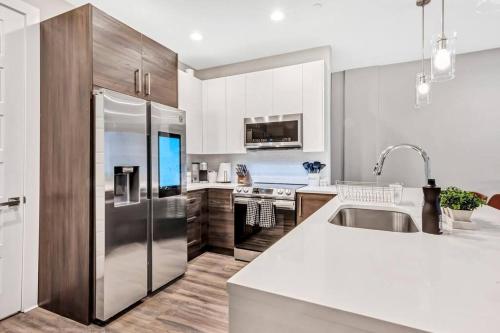 a kitchen with white cabinets and a stainless steel refrigerator at Private Rooftop Patio + 4 Story Home in Downtown FW in Fort Worth