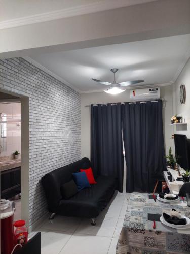 a living room with a black couch and a brick wall at Apartamento Edifício Turim Ponta da Praia Santos in Santos