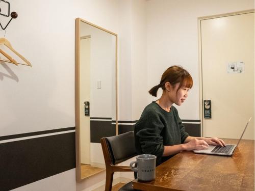 a woman sitting at a table using a laptop computer at HOTEL GRAPHY NEZU - Vacation STAY 82511 in Tokyo