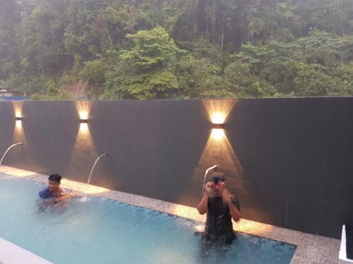 a man taking a picture of another man in a swimming pool at Shafickza Guesthouse in Kuala Terengganu