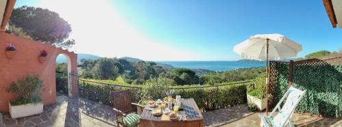 a patio with a table and an umbrella at Ca' La Stella Sea-view Apartments in Porto Azzurro