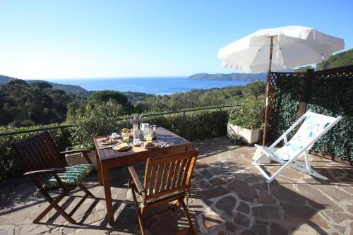a table and two chairs and an umbrella on a patio at Ca' La Stella Sea-view Apartments in Porto Azzurro