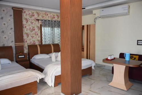 a hotel room with two beds and a table at Royal Sundarban Wild Resort in Jharkhali