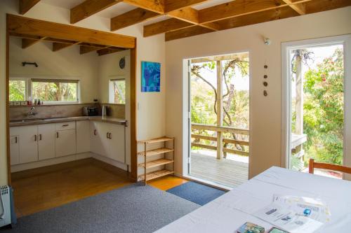 a kitchen with a table and a sliding glass door at Fern Lodge Coromandel in Coromandel Town