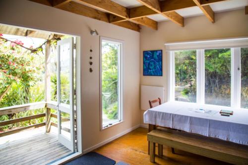 Schlafzimmer mit einem Bett und großen Fenstern in der Unterkunft Fern Lodge Coromandel in Coromandel Town