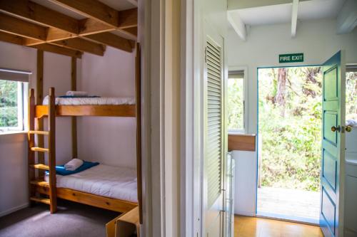 a bedroom with bunk beds and a door to a room at Fern Lodge Coromandel in Coromandel Town