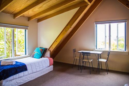 a attic bedroom with a bed and a table at Fern Lodge Coromandel in Coromandel Town