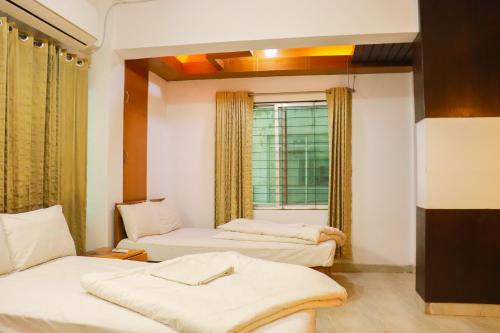 a room with three beds and a window at Cox Hill Tower in Cox's Bazar