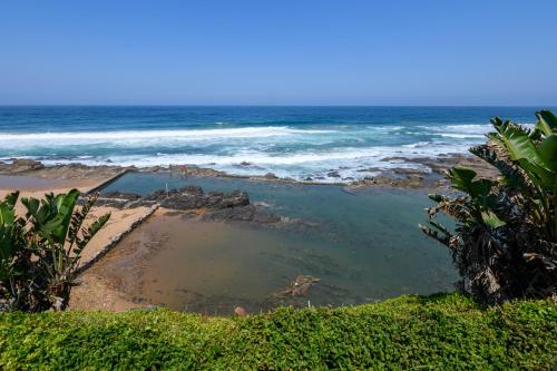 a beach with a pool of water next to the ocean at Chakas Cove in Ballito