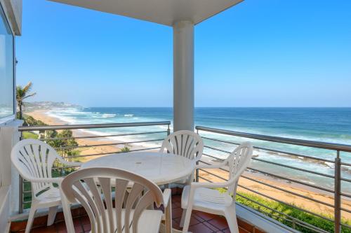 a table and chairs on a balcony with the ocean at Chakas Cove in Ballito