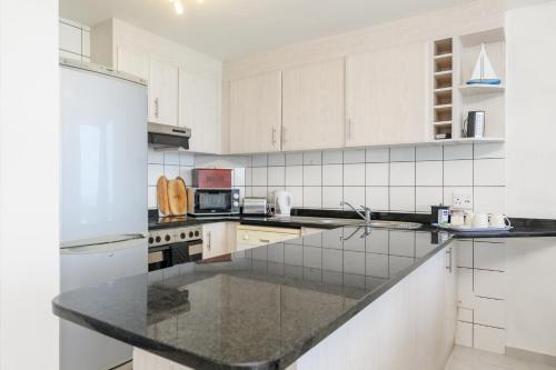 a kitchen with white cabinets and a black counter top at Chakas Cove in Ballito