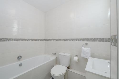 a white bathroom with a toilet and a bath tub at Chakas Cove in Ballito