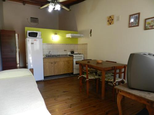 a kitchen with a table and a white refrigerator at Complejo Los Molles in Potrero de los Funes