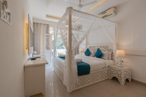 a bedroom with a white canopy bed with blue pillows at Lillywoods Zac Beach Resort, Calangute in Goa Velha