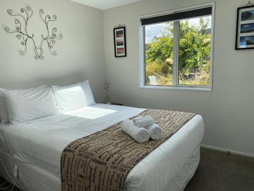 a bedroom with a bed with two towels on it at Mahina Cottage in Twizel