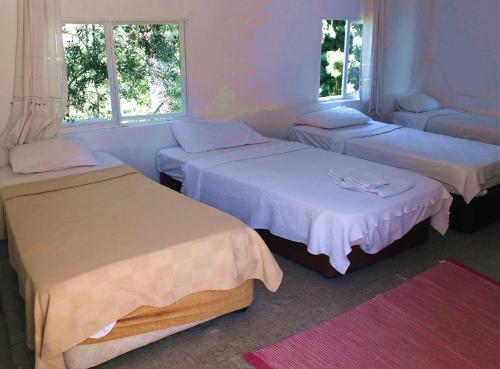 a room with three beds and two windows at Bircan Hotel in Bodrum City