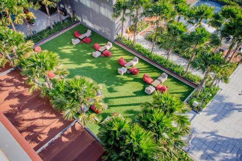 - une vue sur une pelouse avec des chaises et des palmiers dans l'établissement Aisana Hotel Korat, à Nakhon Ratchasima