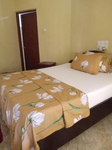 a bed with a blanket with white flowers on it at No.11 Uptown EconoStay in Kandy
