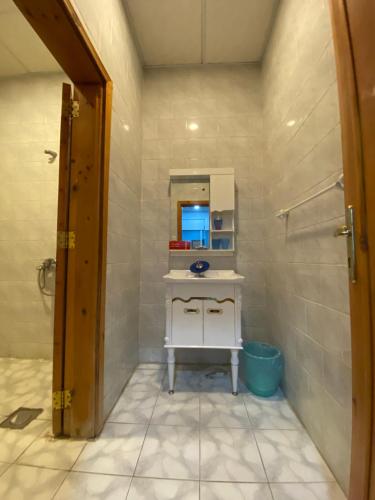 uma casa de banho com um lavatório, um espelho e um chuveiro em روز الهدا em Al Hada