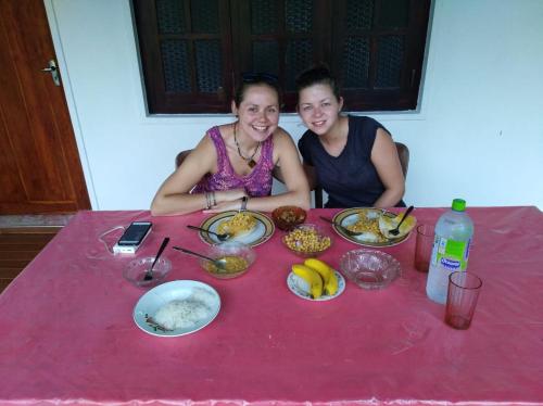 two women sitting at a red table with food at Deer Garden Guest in Polonnaruwa