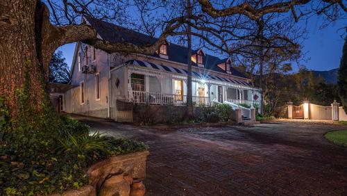 a large white house with a tree in front of it at De Oude Pastorie in Swellendam