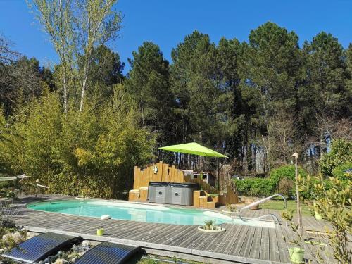 una piscina con mesa de picnic y sombrilla en Les Hôtes Landes, en Saint-Gor