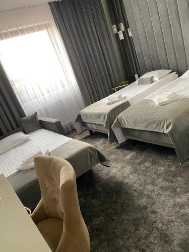 a hotel room with two beds and a chair at Hotel & Spa Biały Dom in Gliwice