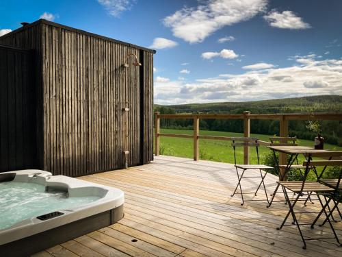 a deck with a hot tub and a table and chairs at Stilleben Hotell in Åmot