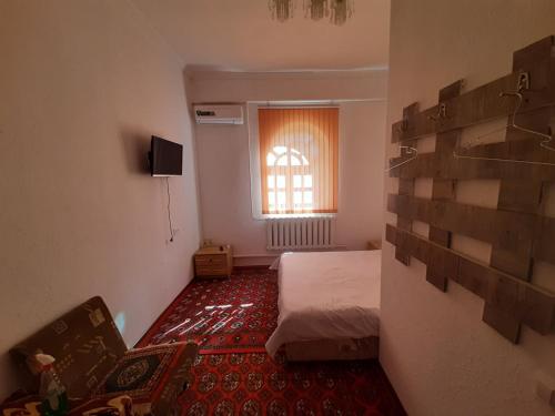 ヒヴァにあるRoyal Khiva Hotelのベッドと窓が備わる小さな客室です。