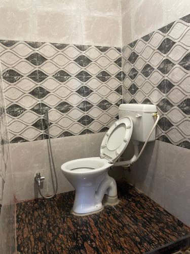 a bathroom with a toilet in a tiled room at Hotel Royal Embassy in Tinsukia