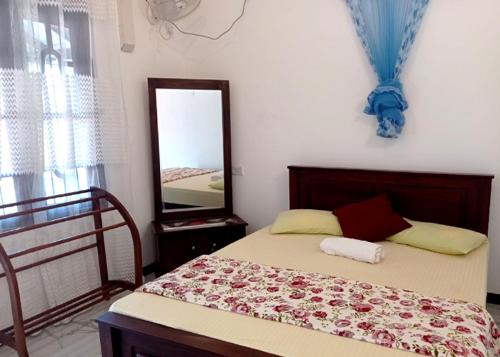 Schlafzimmer mit einem Bett und einem Spiegel an der Wand in der Unterkunft Arusha Guest House in Negombo
