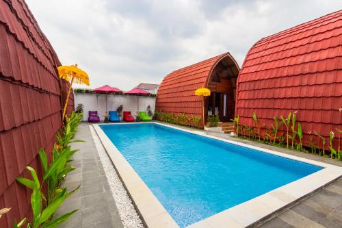 a swimming pool in front of a house with a red roof at Omah Lumbung Yogyakarta in Seturan