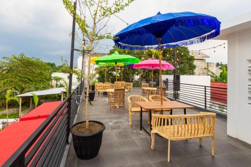 a patio with tables and umbrellas on a roof at Omah Lumbung Yogyakarta in Seturan
