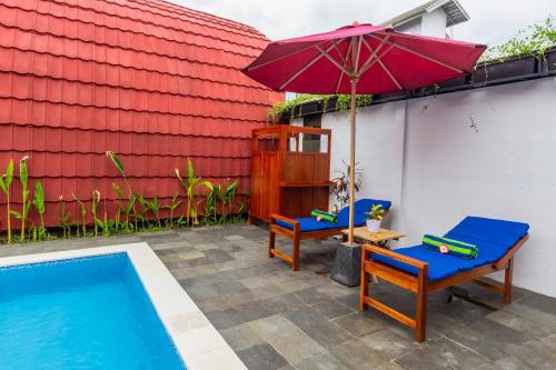 a patio with two chairs and an umbrella next to a pool at Omah Lumbung Yogyakarta in Seturan