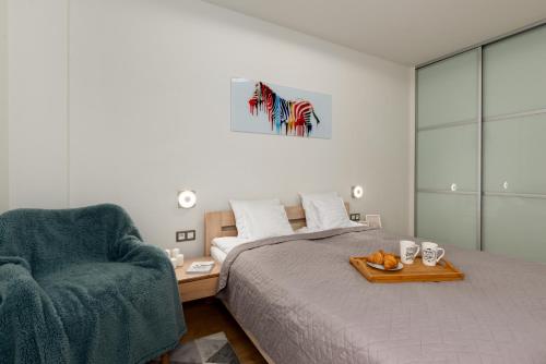 a bedroom with a bed and a chair with a tray of fruit at Apartament 14ka. Ustroń in Ustroń